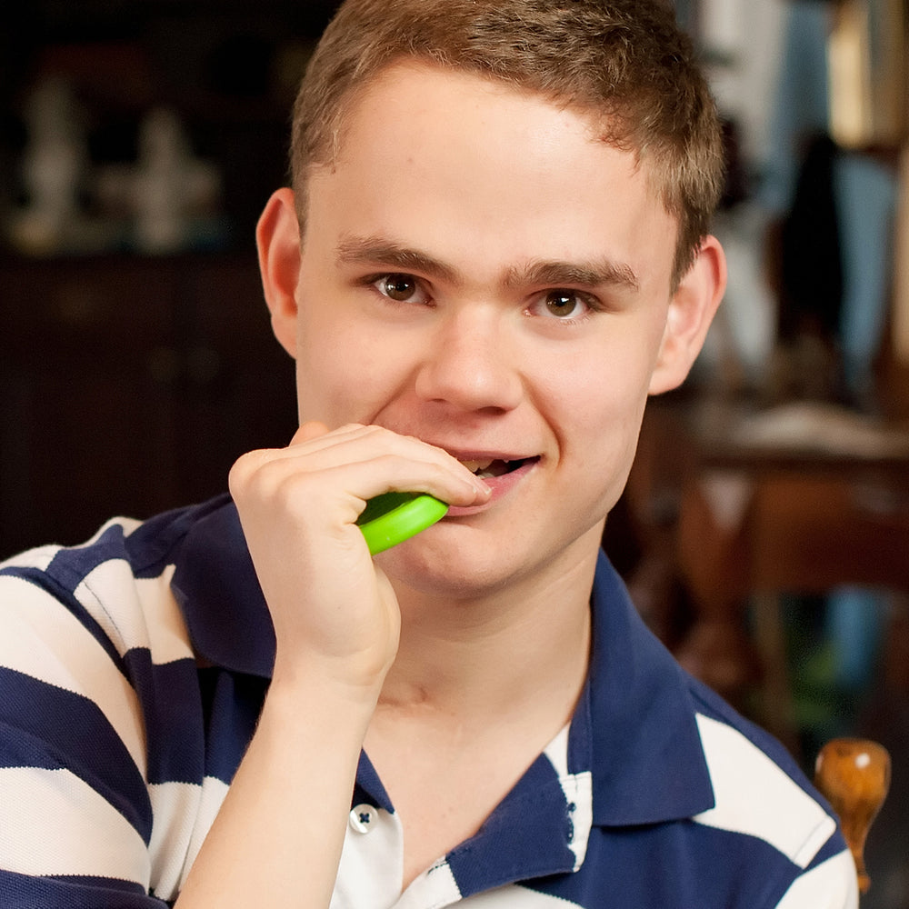 A teen with light skin tone and short brown hair holds the Lime Green Grabber Original up to their mouth.