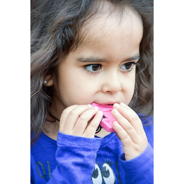 A child with medium skin tone and long brown hair holds a Diamond Chewable Jewel Necklace up to their mouth. They have as mall portion in their mouth.