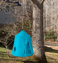The Go! HangOut HugglePod hanging from a tree in a yard. There is a house behind it.