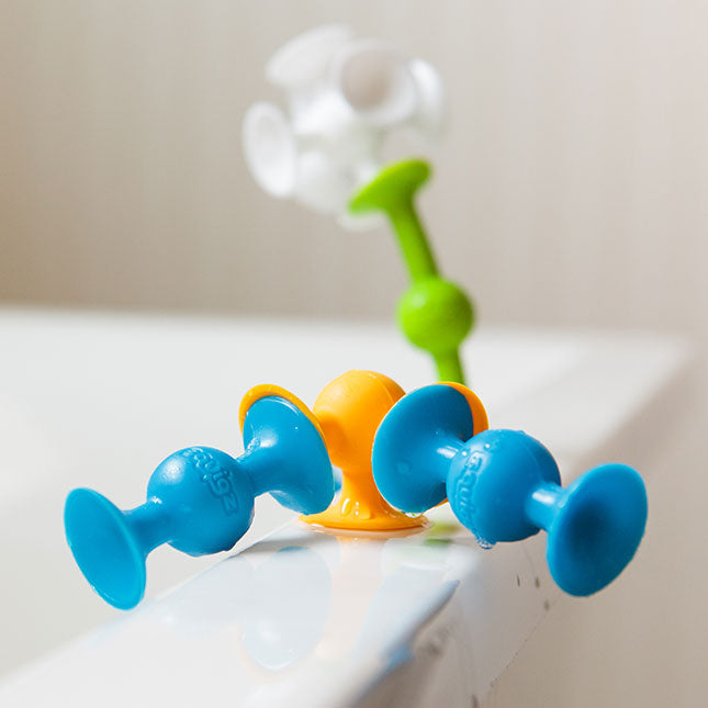 Several Squigz are connected on the edge of a bathtub.