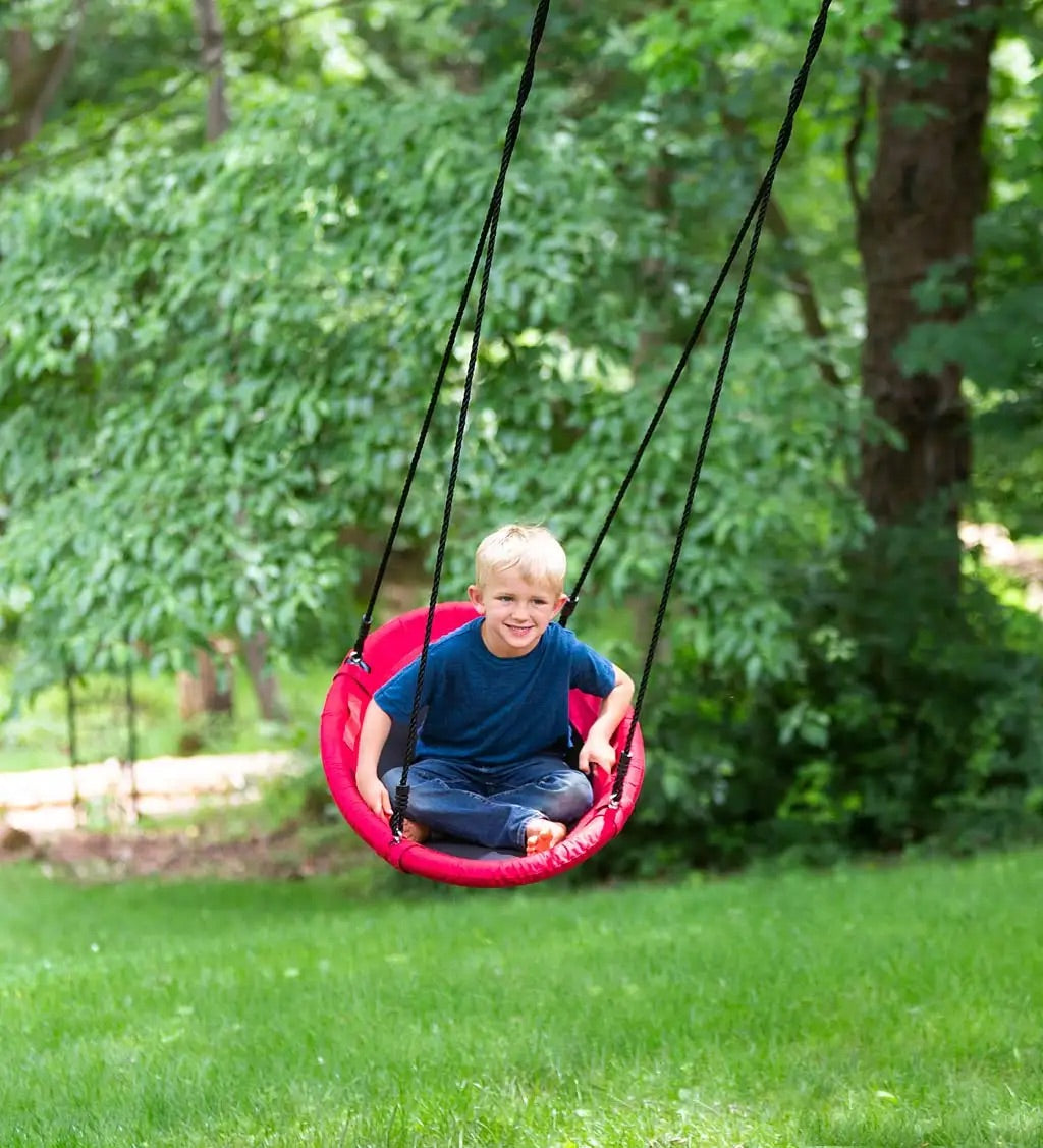 A child with light skin tone and short light blonde hair is swinging back on the Sensory Snuggle Oval Swing while smiling.