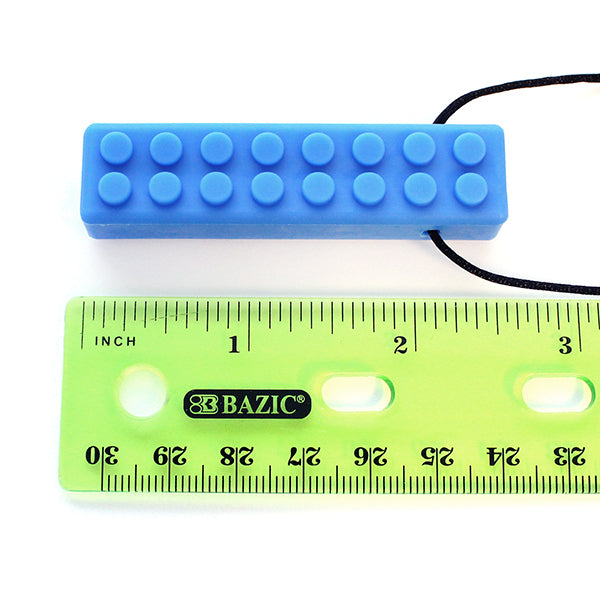 The blue Brick Stick Chew Necklace pendant next to a ruler, measuring 2.5".