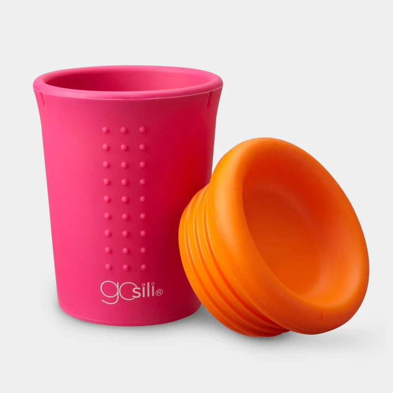A pink cup with an orange lid next to it.
